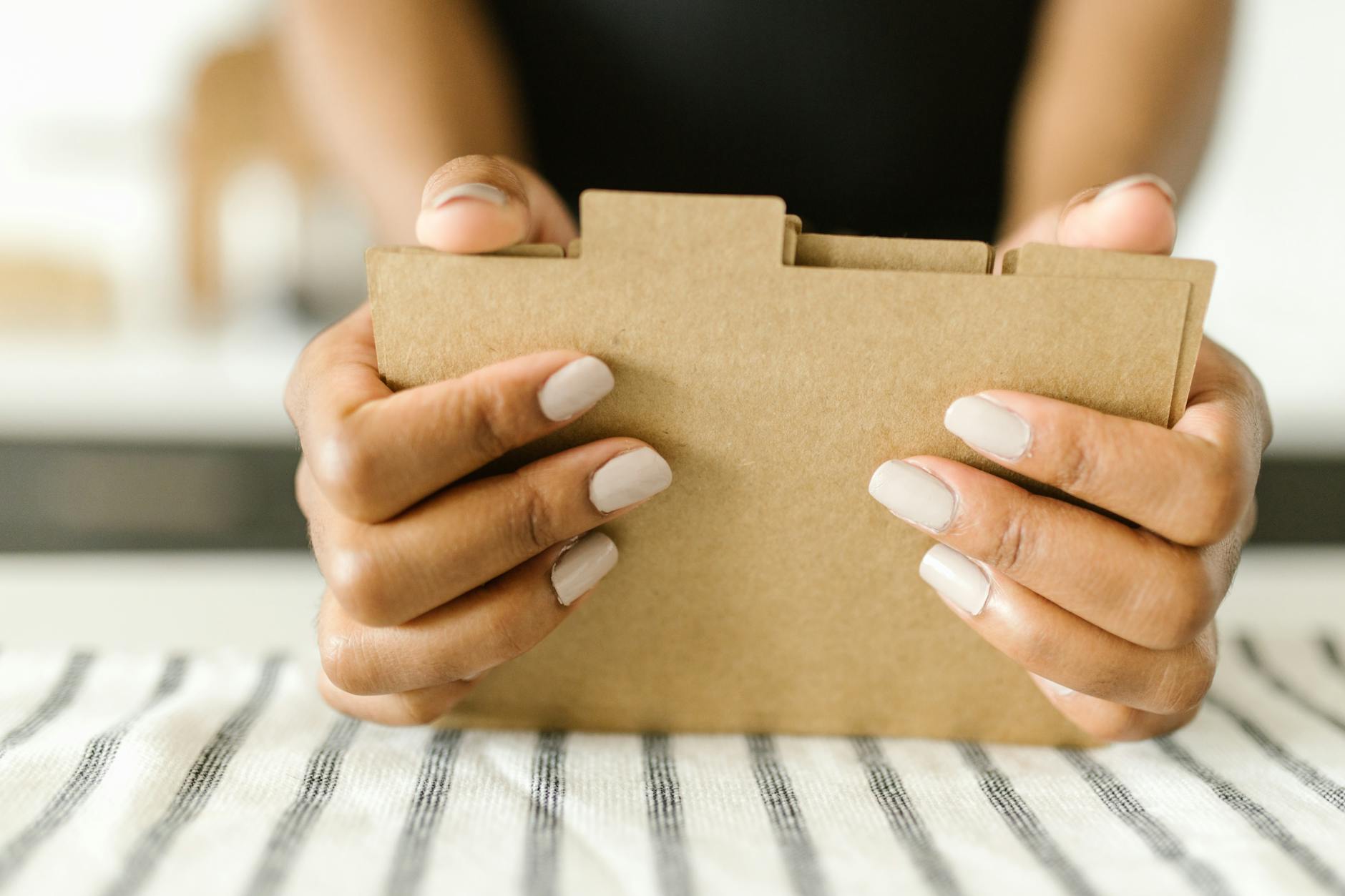 Klasyfikacja akt w projektach kulturalnych: jak nie mieszać finansów i programu Dłonie z zadbanym manicure trzymają brązową teczkę z dokumentami