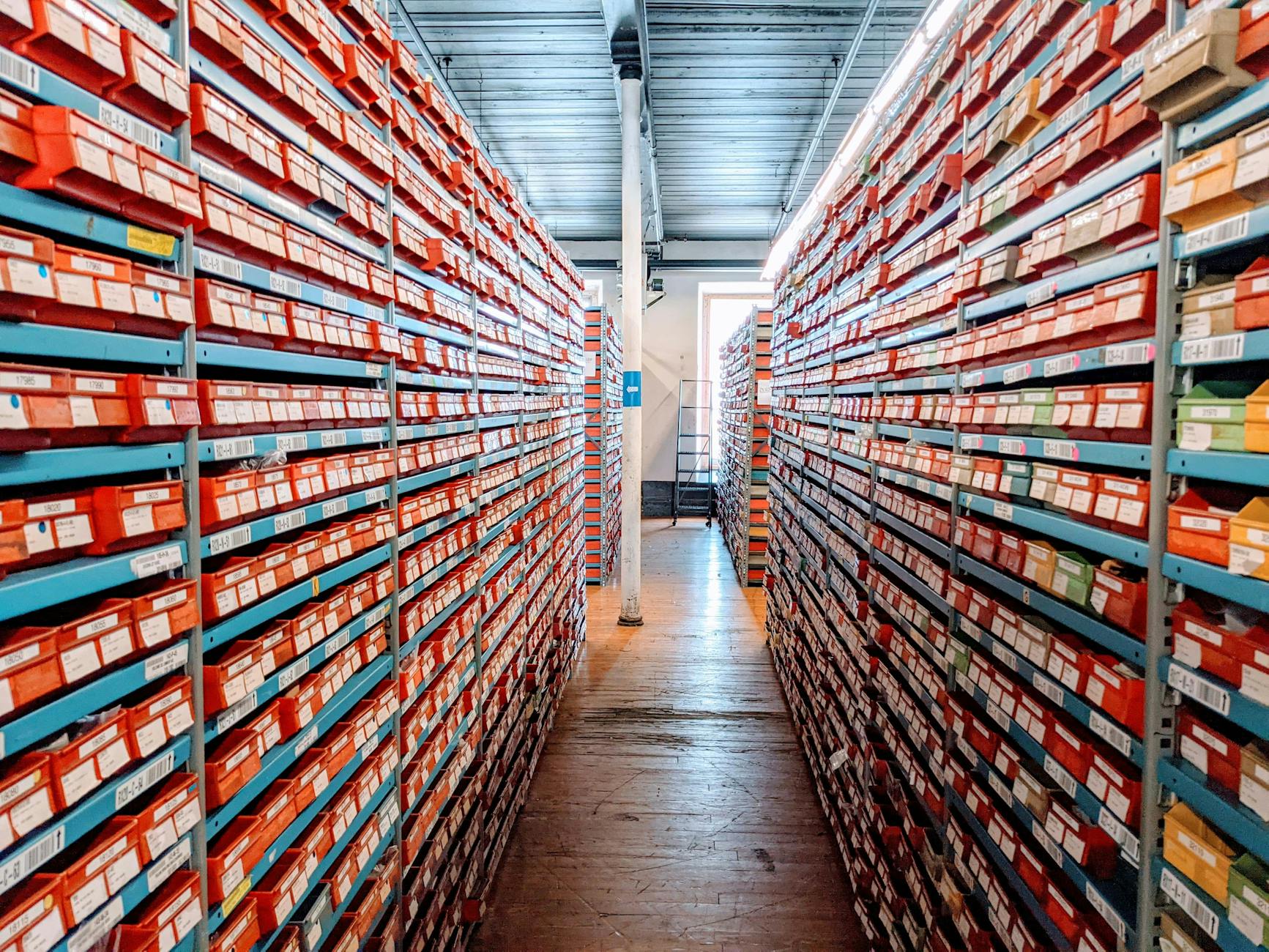 Rząd regałów w magazynie z czerwonymi pudełkami butów jako ewidencja zapasów