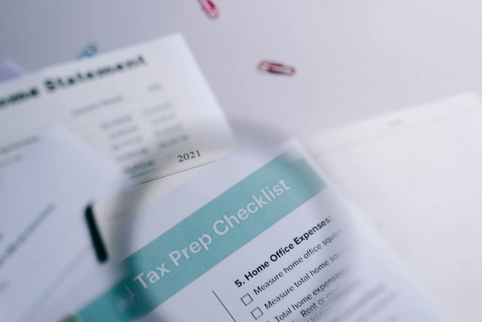 Zbliżenie na papierową checklistę i zestawienie przychodów z spinaczami